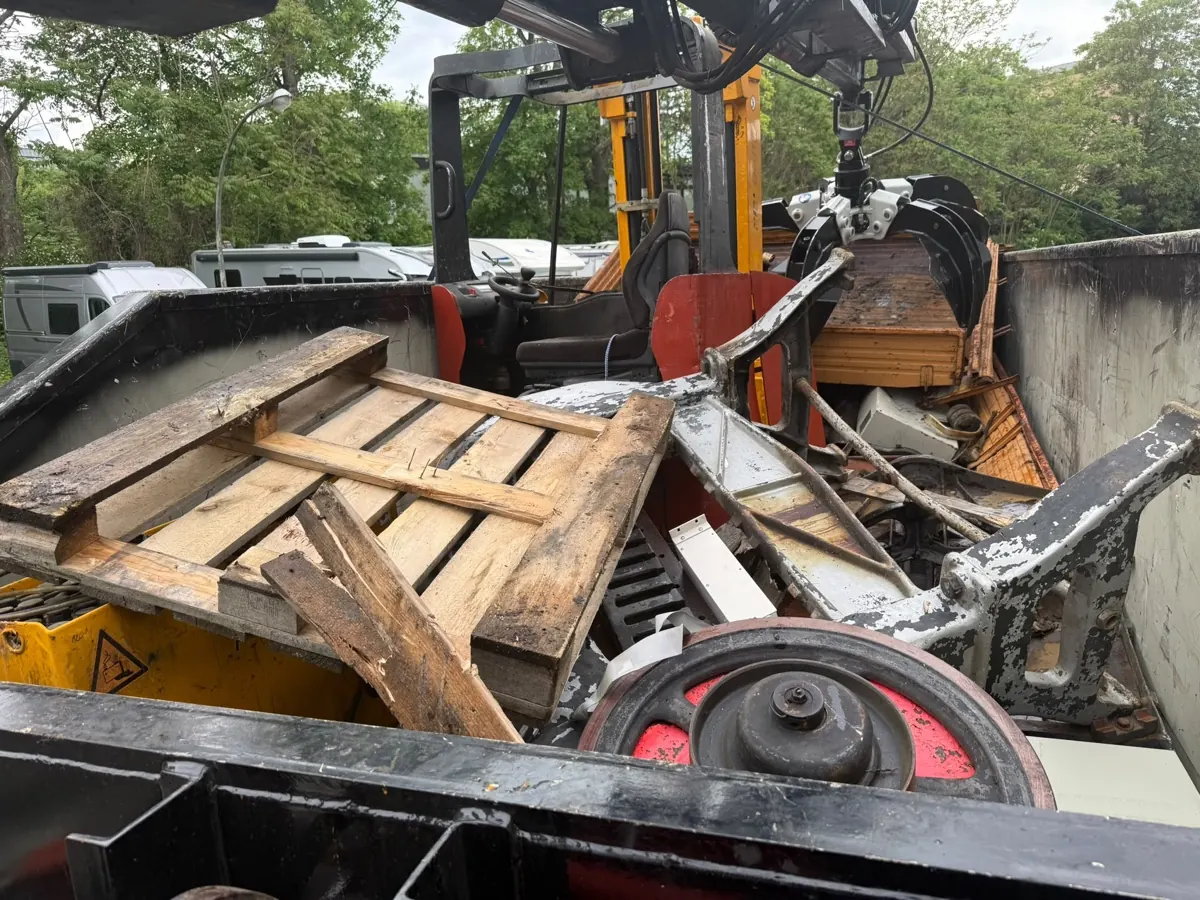 Greifer verlädt Altmetall in einen Container