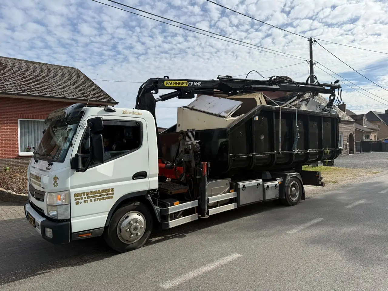 Lkw mit Ladekran und Abrollcontainer von Metsemakers auf der Straße